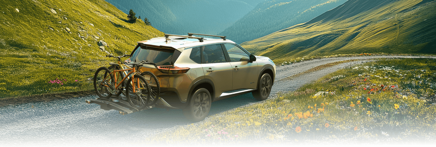 Nissan X-Trail mit beladenem Fahrradträger fährt durch eine farbenfrohe Frühlingslandschaft.